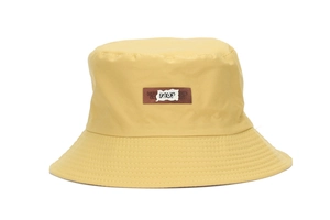 Detailed view of yellow bucket hat with embroidered letter patch and stitched brim