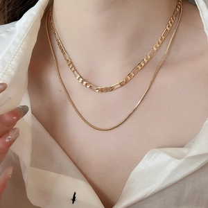 Close-up of layered 18k gold plated Figaro and snake chains worn by a model