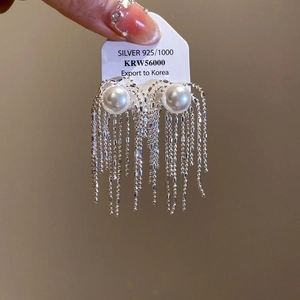 Detail of silver drop earrings with white pearls and long tassel chains on a 925 silver tag