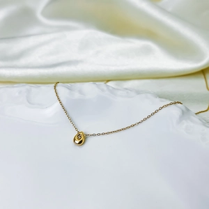 Close-up of a gold water-drop pendant with a zircon on white silk fabric background