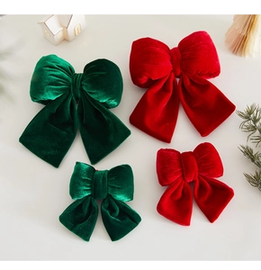 Detail of red and green velvet Christmas bows showing size comparison and plush texture