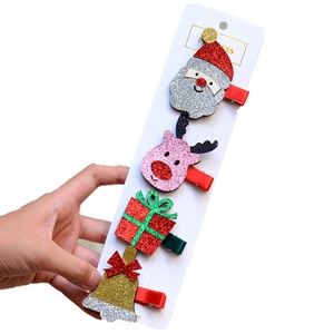 Close-up of four glittery Christmas hair clips featuring Santa, reindeer, gift box and bell