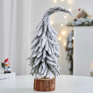 Close-up of a mini snow-covered PE Christmas tree with a curved top and natural wooden base