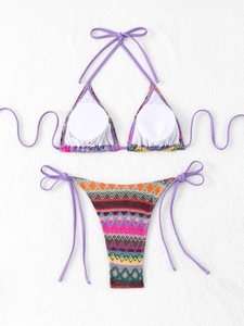 Flat lay of zig-zag patterned bikini set with purple ties on textured background