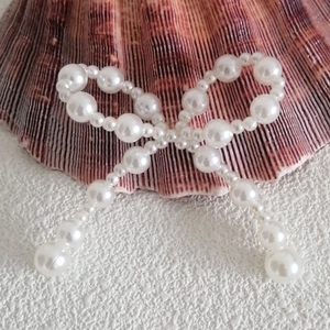 Close-up of a white pearl bow accessory placed on a textured reddish seashell