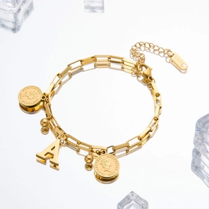 Close-up of gold double chain bracelet with queen coin pendant and letter A charm