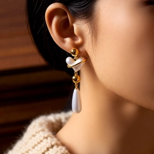 Close-up of vintage heart and pearl drop earrings on a model in a warm setting