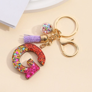 Macro detail of resin letter Q keychain with colorful sequins and purple tassel