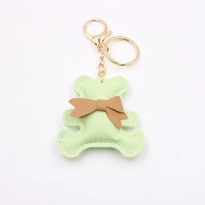 Detail of light green PU leather bear keychain with brown bow and gold metal hardware