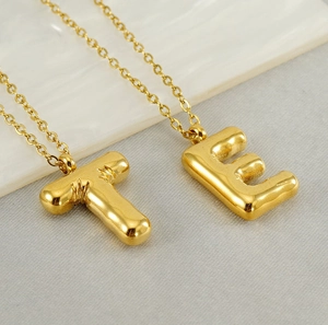 Détail des pendentifs lettres T et E dorés style bulle sur des chaînes polies brillantes