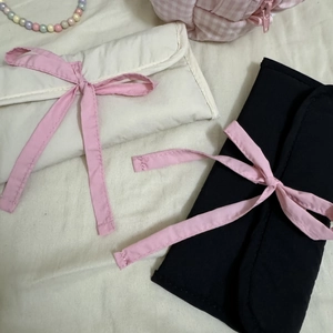 Détail des trousses à papeterie style ballet avec rubans roses sur fond textile blanc