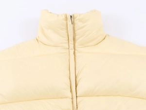 Detail view of cream yellow padded vest featuring a stand collar and smooth central zipper
