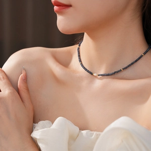 Detail of beaded titanium steel necklace with blue faceted stones and a freshwater pearl