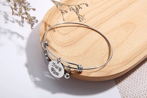 Macro-opname van zilveren rvs armband met hartvormige hanger en True Love gravure