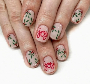 Gros plan d'ongles de Noël rose nude avec baies rouges, neige et lettrage Joy élégant