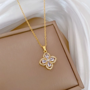 Detailed view of a gold clover pendant with sparkling zircons on a brown jewelry tray