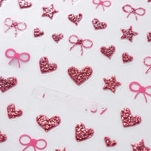 Macro detail of pink glitter nail stickers featuring heart and bow-knot patterns
