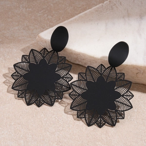 Macro detail of matte black geometric flower earrings with laser-cut mandala patterns