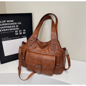 Detail view of brown leather tote bag with external pockets and adjustable strap