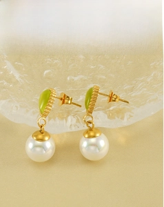 Detail of gold teardrop earrings with green opal and white pearls on textured fabric