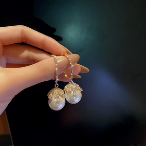 Detailed shot of gold hoop earrings featuring large round pearls and sparkling zircons