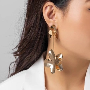 Gros plan sur de grandes boucles d'oreilles dorées à fleurs sur un modèle élégant