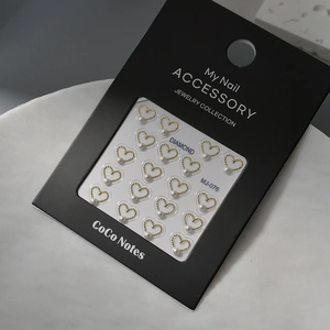 Close-up of gold heart nail charms with pearls and MJ-076 model details on packaging