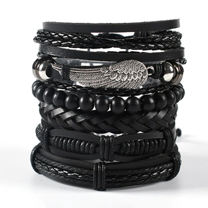 Detail of layered black leather bracelets with metallic wing charm and beads on stand
