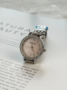 Close-up of a silver ladies watch with rhinestone bezel and pink mother-of-pearl dial