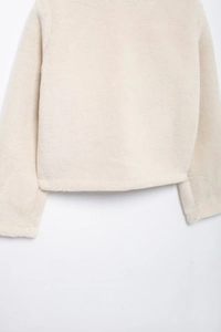 Detail of soft cream faux fur texture on sleeve and hem of a minimalist short jacket