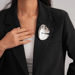 Abstract silver geometric brooch with liquid metal texture on black blazer jacket