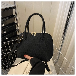 Detail of black shell bag featuring crocodile-embossed texture and gold-tone zippers