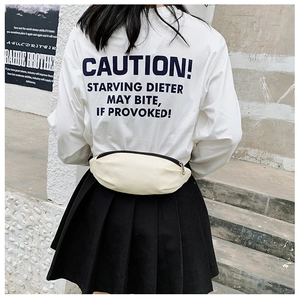 Detail view of a minimalist cream white canvas waist bag worn on a street style background