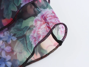 Detail aus transparentem Organza-Stoff mit Blumenmuster und schwarzen Saumkanten