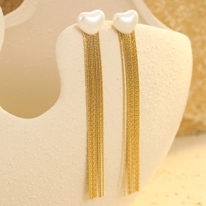 Detailed macro view of heart studs with gold tassel chains on beige background