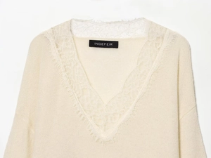 Detailed macro view of the delicate lace trim on a cream V-neck wool blend sweater
