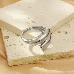 Macro shot of silver liquid metal irregular ring on textured stone and satin background