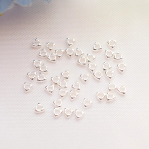 Polished silver triangle spacer beads for DIY jewelry making on white fabric