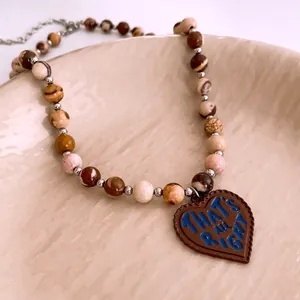 Vintage stone beaded necklace with a brown heart pendant and blue text detail
