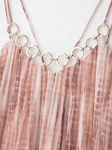 Detalle de vestido tie-dye de gasa plisada rosa y marrón con anilla metálica decorativa