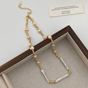 Detailed close-up of Baroque pearl necklace with gold threaded chain and lobster clasp