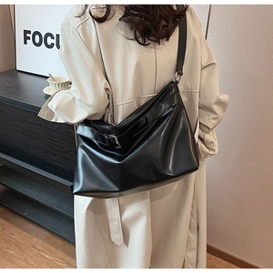 Détail d'un sac d'épaule en cuir souple noir avec bandoulière réglable et boucle en métal