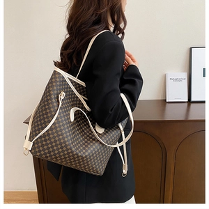 Brown tote bag with yellow floral print and white leather straps shown on shoulder