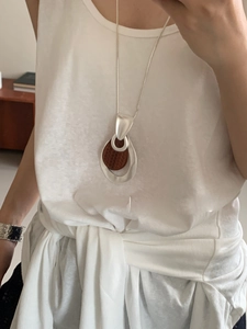 Detail shot of long sweater necklace featuring silver hollow teardrop and wood inlay
