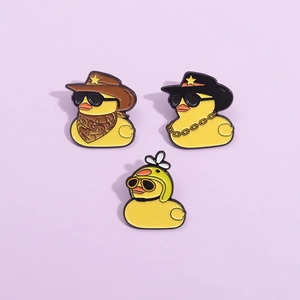 Trois pin's canard jaune en émail avec chapeau de cowboy, chaîne en or et casque de pilote