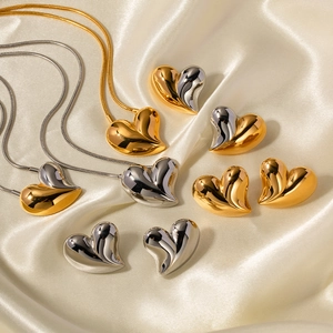 Minimalist 18K gold and silver 3D heart-shaped pendant necklaces on silk background