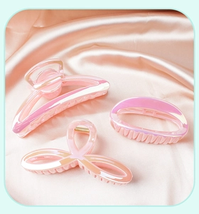 Three pink iridescent hair claws with glossy laser finish on soft silk background
