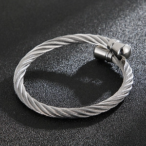 Macro shot of silver twisted cable cuff bracelet with smooth cylindrical ends on dark background