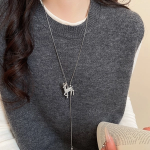 Silver sweater chain with a sparkling reindeer pendant worn over a grey knit vest