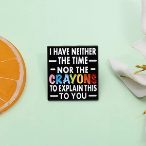 Square black enamel pin with colorful humorous text I Have Neither The Time Nor The Crayons